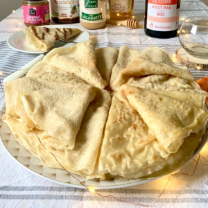 Des crêpes pliés en triangles sont sur une assiette.